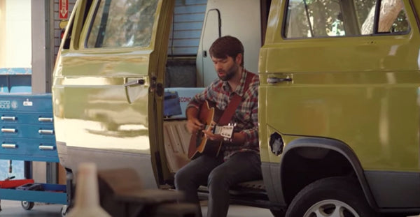 Pictured: Joel Van Horne stands with a guitar in front of a green camper van