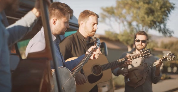 Pictured: Two men playing guitar in front of a camper van