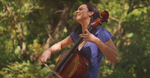 Pictured: Sam Rae sitting in a forest playing the cello