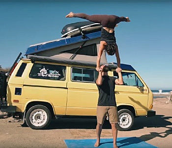 Pictured: couple performing acroyoga in front of a yellow van
