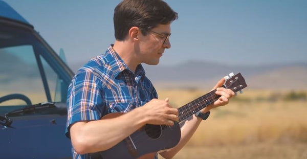Pictured: Scott Garred playing guitar in front of a camper van